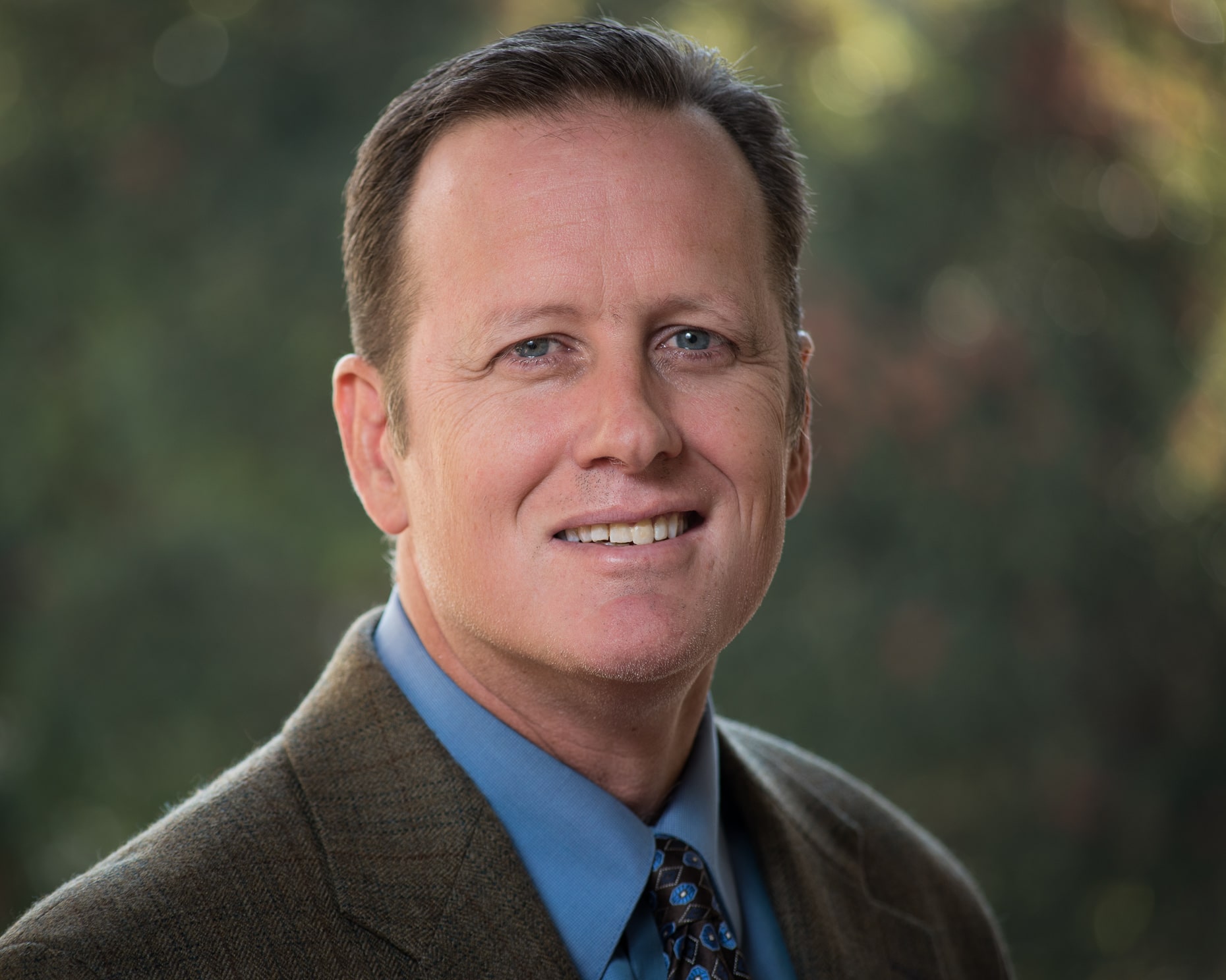 A man in a suit and tie smiling for the camera.